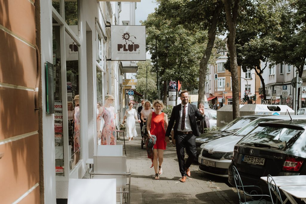 Gäste einer Hochzeit laufen über die Ackerstrasse in Düsseldorf Fliegern