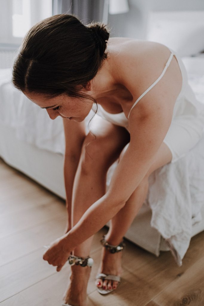 Braut zieht sich beim Getting Ready die Schuhe an