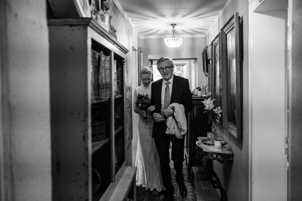 Brautvater führt Braut durch einen Flur zu ihrem Bräutigam