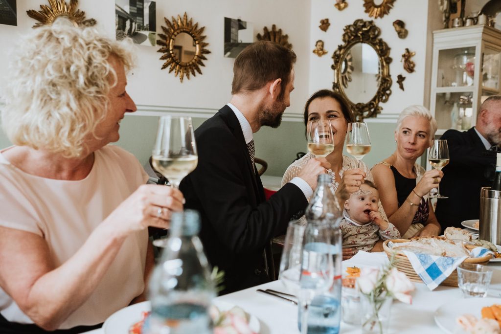 Brautpaar stösst mit Sekt mit seinen Gästen am Tisch an