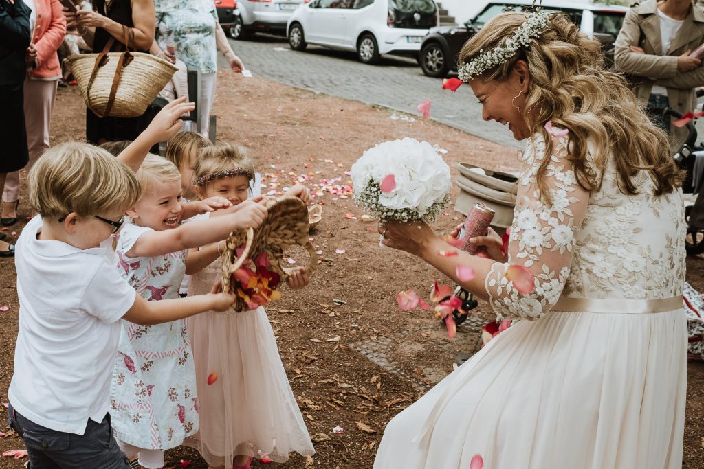 Braut wird von den Blumenkindern mit Blüten beworfen