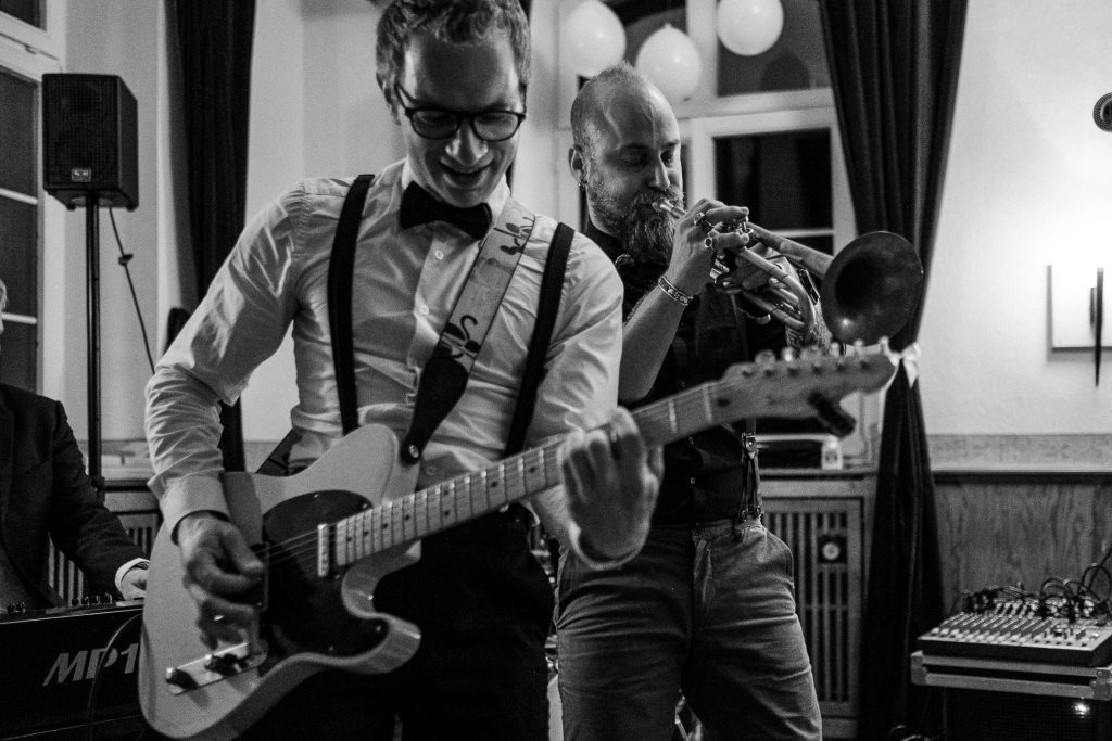 Bräutigam spielt Bass und ein Bandmitglieder Trompete während der Hochzeit in der Klosterruine Allerheiligen