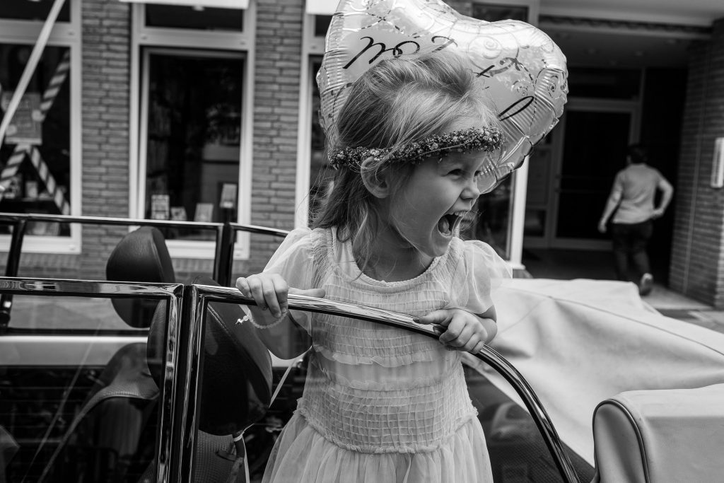 Blumenmädchen schaut aus einem Käfer Cabrio heraus und freut sich