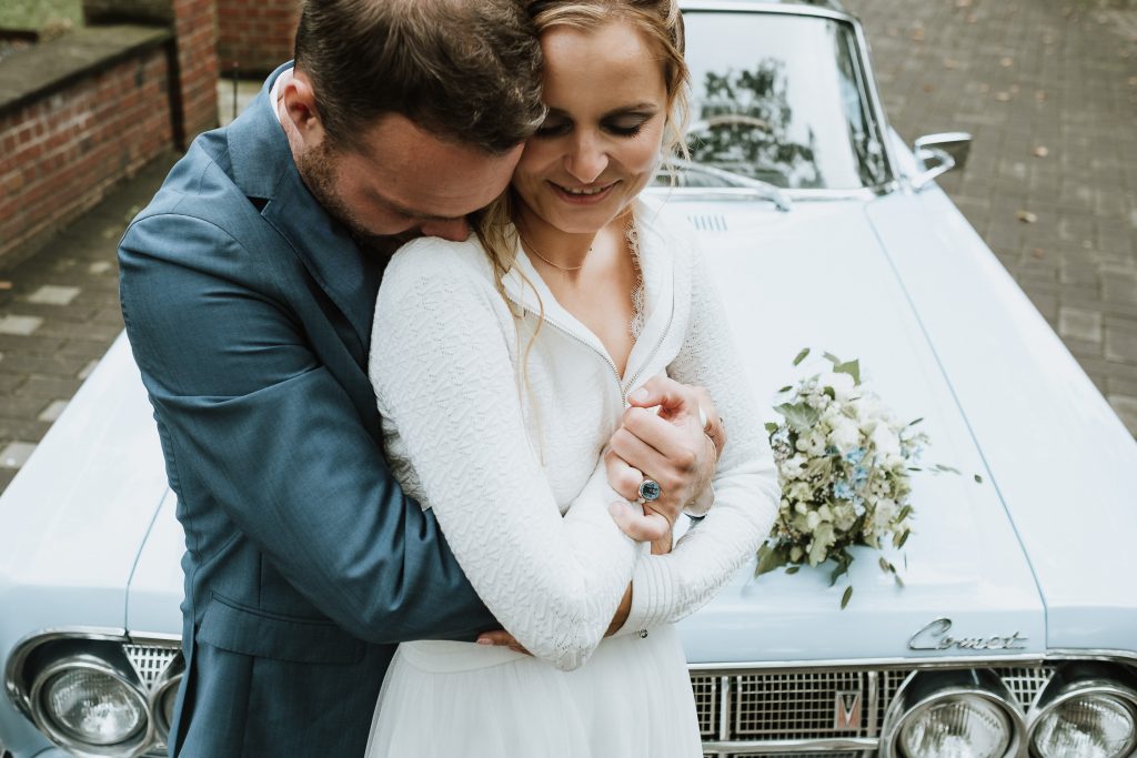 Portrait eines Brautpaares vor einem Oldtimer