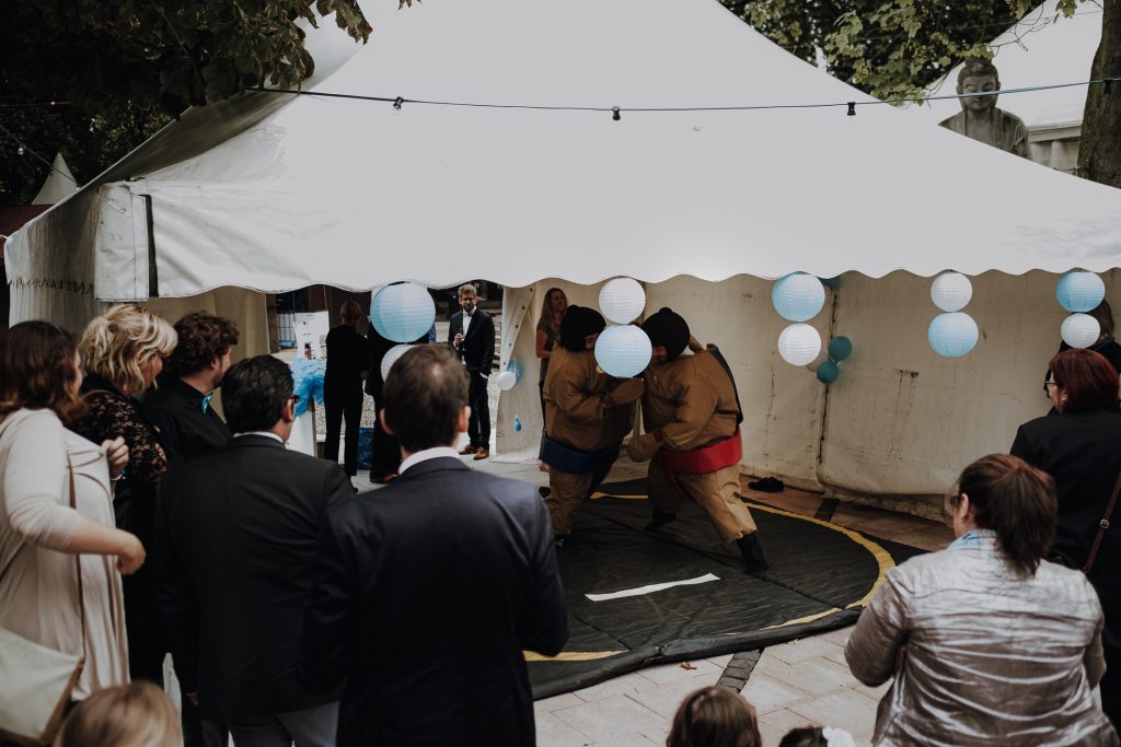 Hochzeitsgesellschaft in vor einem Zelt in dem mit Summe Anzügen gerungen wird