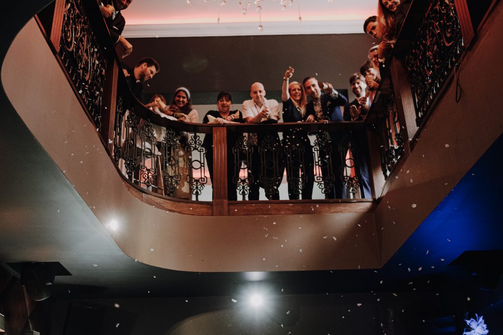 Gäste einer Hochzeitsgesellschaft schauen von einer Galerie herunter auf die freie Trauung