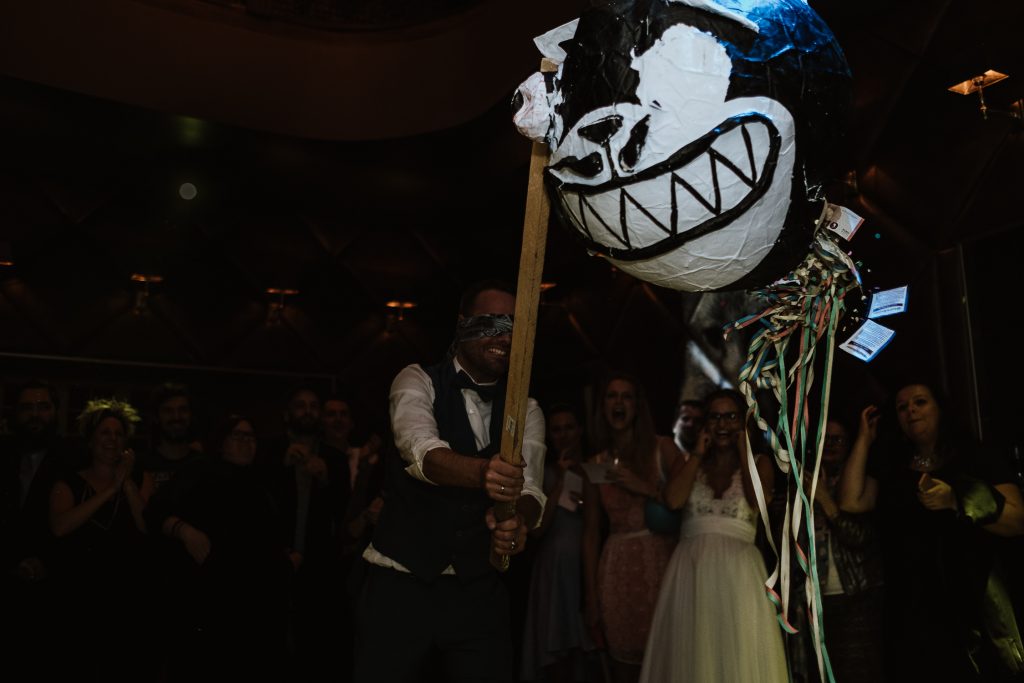 Bräutigam haut mit einem Holzstock auf eine Pinata in der Villa Rheinperle in Duisburg