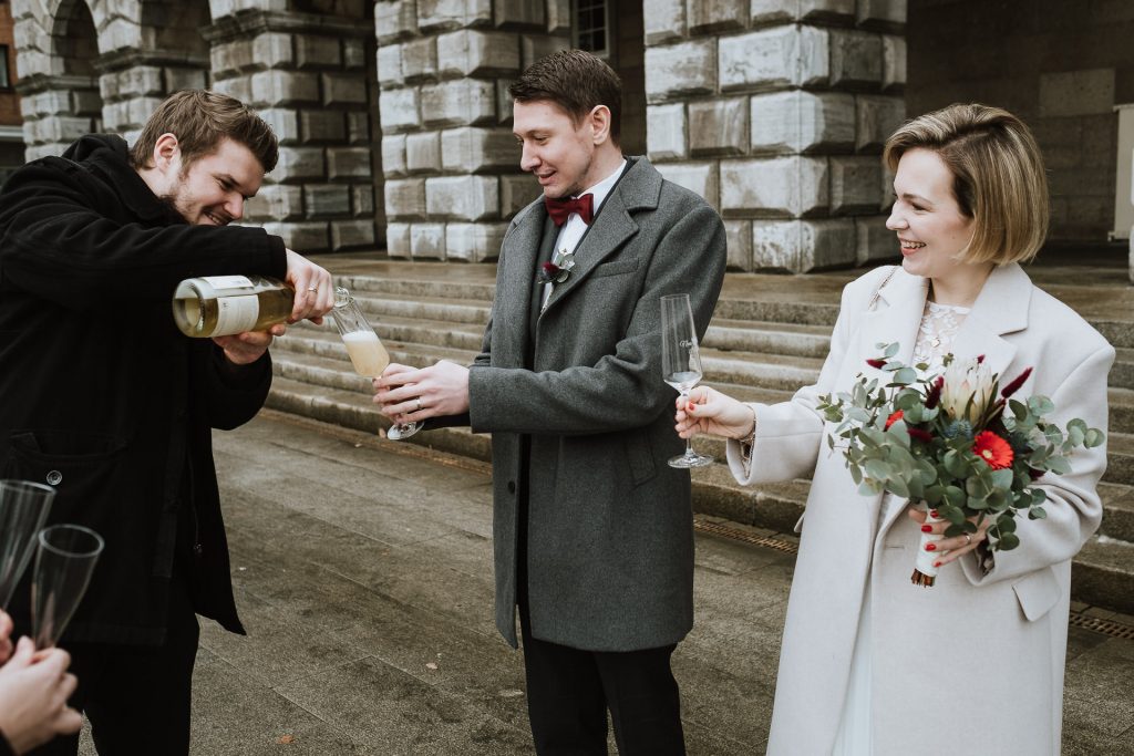 Brautpaar stößt mit Trauzeugen vor dem Standesamt Mühlheim mit Sekt an